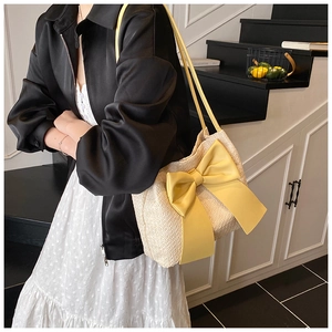 Détail du sac cabas tissé crème avec un grand nœud jaune et des doubles bandoulières