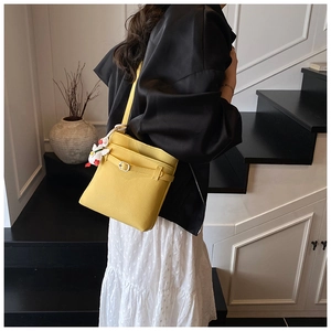 Sac seau jaune motif litchi avec breloque peluche canard blanc sur escalier