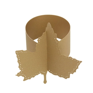 Macro view of gold maple leaf paper napkin ring with delicate laser-cut hollow pattern
