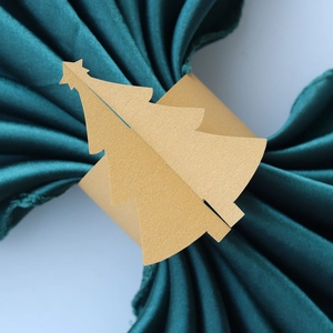 Gros plan d'un rond de serviette en papier doré en forme de sapin sur satin vert