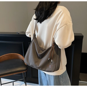 Detail der minimalistischen dunkelbraunen Hobo-Tasche mit TCT-Logo und braunen Lederbändern