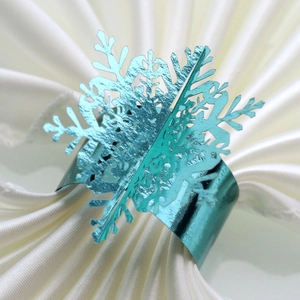 Macro view of green metallic snowflake napkin ring on white fabric background