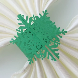 Close-up of green laser-cut paper snowflake napkin rings for Christmas table decor