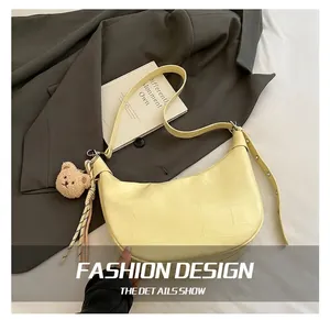 Detail of pale yellow crocodile embossed hobo bag with teddy bear charm and strap
