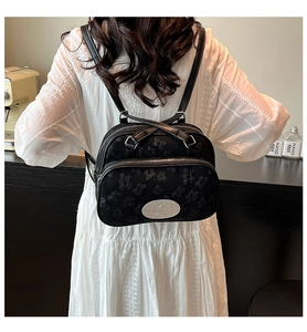 Détail d'un sac à dos en jacquard noir avec zips argentés et plaque logo métallique