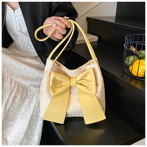 Vue détaillée d'un sac seau en paille beige orné d'un grand nœud décoratif jaune vif