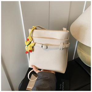 Gros plan sur le sac seau en cuir grainé beige avec boucle et charm canard jaune