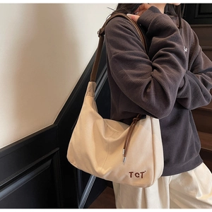 Detail einer beigen Canvas-Tasche mit brauner TCT-Stickerei und Leder-Schultergurt