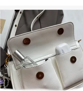 Detail view of white leather crossbody bag with dual magnetic pockets and interior storage