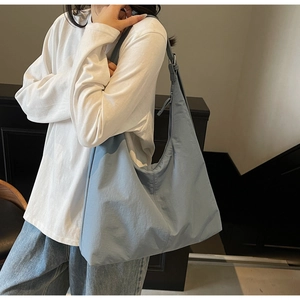 Light blue large capacity tote bag with adjustable strap worn by model in casual style