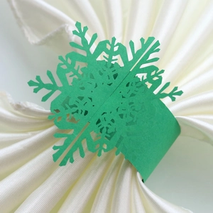 Macro detail of laser-cut green snowflake napkin ring with intricate hollow design