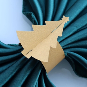 Détail d'un rond de serviette sapin de Noël en papier doré sur tissu en satin vert
