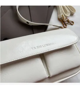 Detailed close-up of white leather flap bag with gold hardware and embossed logo