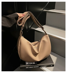 Close-up of beige lychee grain leather hobo bag with metal zipper on a book prop