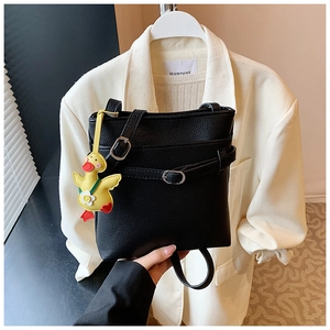 Détail du sac seau noir grainé avec un porte-clé canard en peluche jaune sur la bandoulière