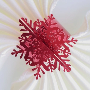 Macro shot of a shiny red metallic snowflake napkin ring on a white fabric background
