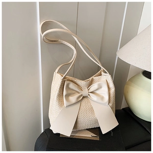 Gros plan détaillé du sac seau en paille avec un grand nœud en cuir et texture tissée