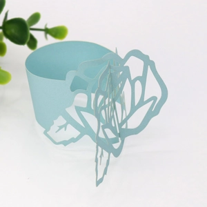 Macro shot of light blue laser-cut paper napkin ring with a hollow rose flower design