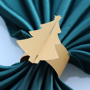 Gros plan de ronds de serviette sapin de Noël dorés sur un tissu en satin vert