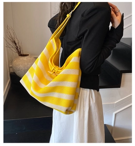 Detail of yellow and white striped woven tote bag with leather strap and wooden horn buckle