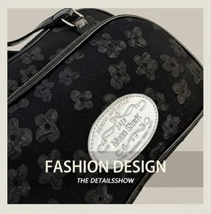 Détail du sac bandoulière noir avec texture florale 3D et plaque logo argentée élégante