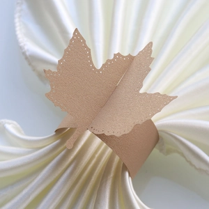 Macro view of a laser-cut gold leaf napkin ring on white satin fabric