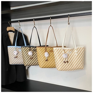 Détail de sacs cabas en paille à rayures multicolores avec pendentifs en peluche