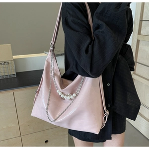 Detail einer großen rosa Schultertasche mit glänzender Textur und weißer Perlenkette Deko