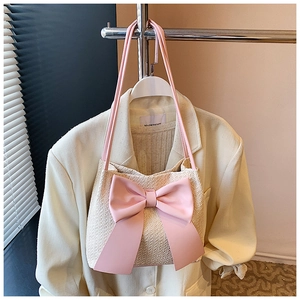 Détail d'un sac seau tissé beige avec un grand nœud rose décoratif sur un blazer