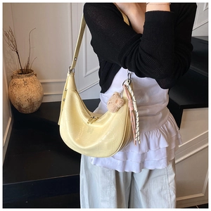 Detail of light yellow crocodile pattern crescent bag with cute plush bear charm
