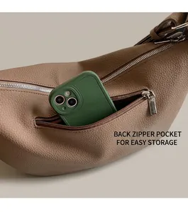 Detailed view of back zipper pocket on brown leather shoulder bag storing a phone