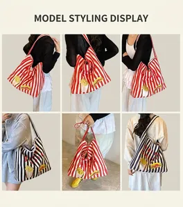 Détail du sac cabas en toile rayée avec écussons brodés porté par un mannequin en intérieur