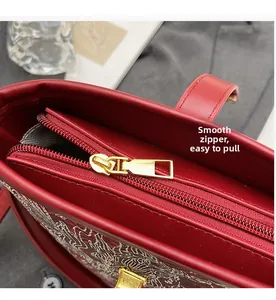 Detail of smooth gold zipper and traditional embroidery on the red leather bucket bag