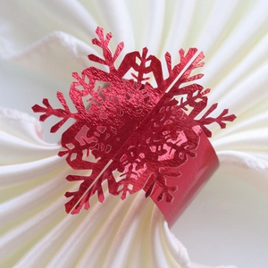 Macro shot of red snowflake napkin ring with metallic luster on white fabric