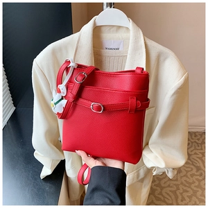 Détail du sac seau rouge à motif litchi avec boucle et charm de dessin animé
