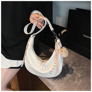 Detail of white croc-effect crescent bag with cute bear charm and woven keychain