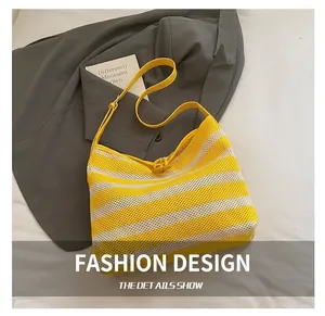 Detail of yellow and white striped mesh tote bag with knot closure on a grey suit