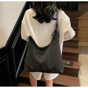 Minimalist black large capacity crescent tote bag shown with an adjustable shoulder strap