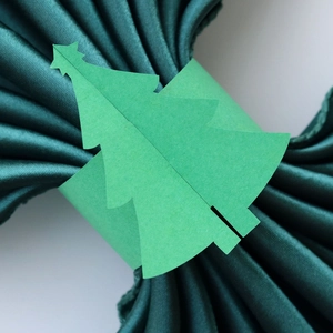 Vue détaillée d'un rond de serviette sapin de Noël en papier sur tissu satiné