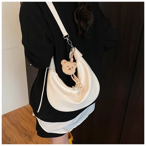 Detail view of white crocodile pattern shoulder bag with a cute brown plush bear charm