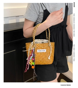 Close-up of a mini straw handbag featuring colorful beads and a star tassel charm