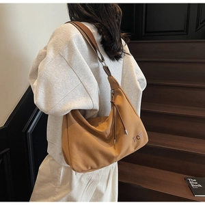 Detail der dunkelkhaki Segeltuch-Tasche mit TCT-Schriftzug auf einer Holztreppe