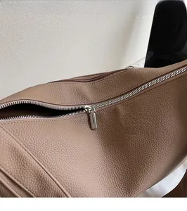 Close-up of premium taupe litchi grain leather texture and smooth silver metal zipper