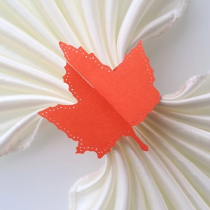 Detailed close-up of orange maple leaf paper napkin ring with elegant cutout borders