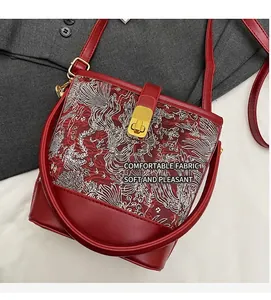 Close-up of red Chinese style bucket bag with white cloud dragon embroidery and gold lock