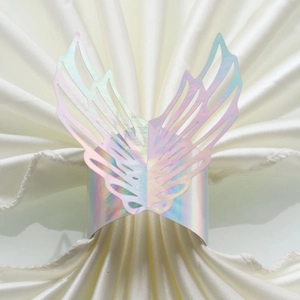 Detail of iridescent holographic angel wing paper napkin ring on a white satin cloth
