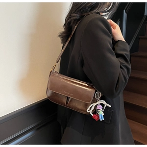 Detail of brown glossy leather shoulder bag with decorative pearl and heart charms