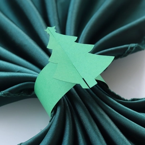 Détail du rond de serviette en papier sapin de Noël vert clair sur tissu satiné