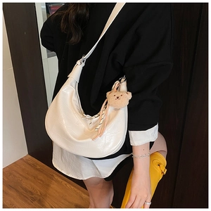 Detailed view of white faux crocodile texture dumpling bag with cute bear charm