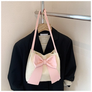 Détail du sac seau tissé crème avec un grand nœud rose et une fine bandoulière en cuir